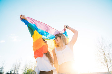 Couple lesbian woman with gay pride flag on the street