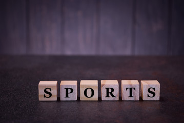 The word sports on wooden cubes, on a dark background, symbols signs