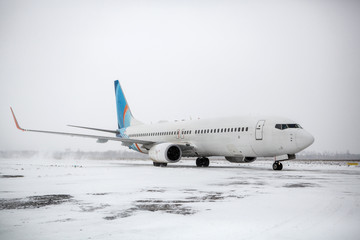 Airliner on runway in blizzard. Aircraft during taxiing on landing strip during heavy snow. Passenger plane in snow at airport.