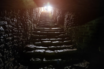 Underground passage under old medieval fortress. Old stone stairs to exit of tunnel