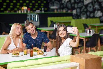 Company looking at phone and taking selfie in cafe