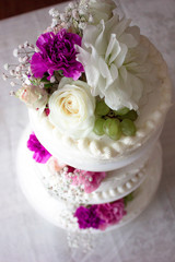Closeup of white wedding cake with  flowers on top.