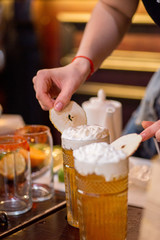 female bartender preparing cocktail in a cocktail bar and decorates the finished drink in a glass
