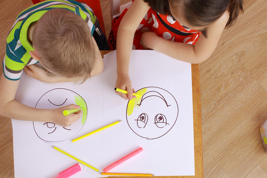 the development of emotional intelligence. child psychology. girl and boy depict different emotions. the girl and the boy draw happy and sad emoticons
