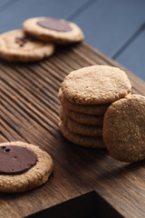 Healthy vegan snack. Homemade oatmeal, peanut and almond cookies with chocolate icing on dark oak board