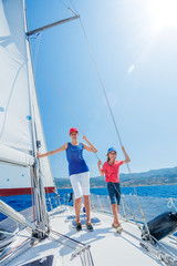 Boy with his sister on board of sailing yacht on summer cruise.