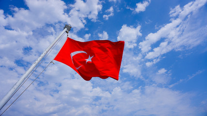 Turkish flag waving in blue sky. National flag of Turkey on flagpole blowing in wind against a blue sky. 19 Mayis Genclik ve Spor Bayrami, 30 Agustos Zafer Bayrami, 29 Ekim Cumhuriyet Bayrami symbol.