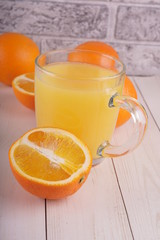 Glass of freshly squeezed orange juice standing on light background with a fresh oranges.  Healthy lifestyle concept