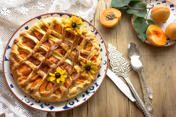 Homemade apricot galette made with fresh organic apricotes on wooden table, top view.