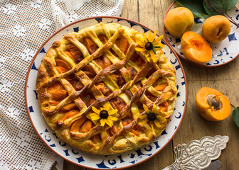 Homemade apricot galette made with fresh organic apricotes on wooden table, top view.