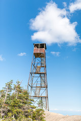 a woman looks out from an old fire tower within the Adirondacks