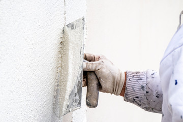 Construction worker plastering and smoothing concrete wall with cement