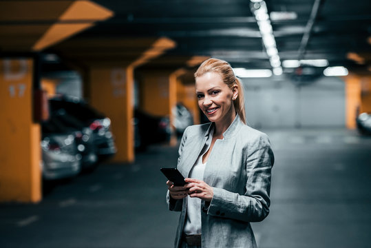 Portrait of a wealthy elegant woman with smartphone in underground parking.