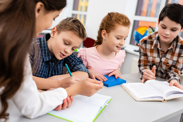 Four pupils with notebook and books at desk in classroom
