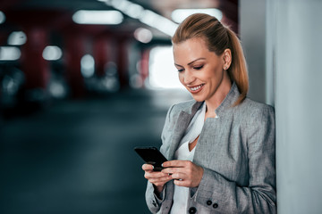 Obraz premium Portrait of a beautiful woman in a suit using mobile phone.
