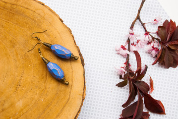 Spring fashion background with pink flowers and bohemian style earrings.