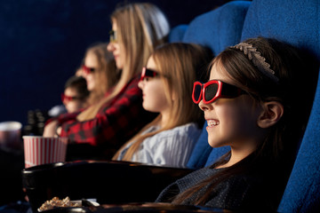 People, kids watchng movie in 3d glasses in cinema.