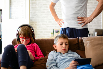 A man begs kids to stop using smartphones. Living room with a light background, horizontal, headphones.
