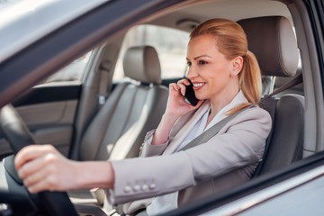 Businesswoman driving and talking on smartphone.