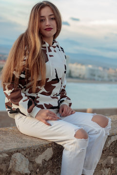 woman sitting on wall facing the sea