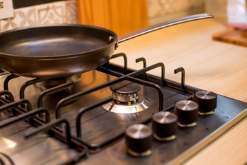 The new frying pan on Brand new gas stove panels.Classic four burner gas stove with brass knobs. Selective focus.Burners on a silver gas stove in the kitchen.gas hob in the kitchen with frying pan