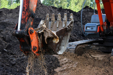 the excavator draws water from the ditch with a bucket where the road will pass. rain season....