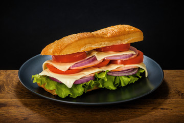 Delicious andwich on the black background and wooden oak table.