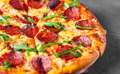 Pepperoni Pizza with Mozzarella cheese, salami, Tomato sauce, pepper, Spices and Fresh arugula. Italian pizza  on Dark grey black slate background