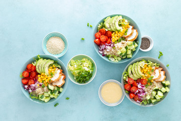 Lunch bowls with grilled cgicken meat, rice and fresh salad of avocado, cucumbers, corn, tomato and onion