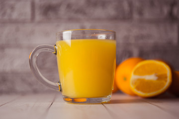 Glass of freshly squeezed orange juice standing on light background with a fresh oranges.  Healthy lifestyle concept