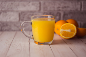 Glass of freshly squeezed orange juice standing on light background with a fresh oranges.  Healthy lifestyle concept