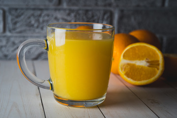 Glass of freshly squeezed orange juice standing on light background with a fresh oranges.  Healthy lifestyle concept
