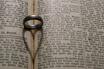 wedding ring with heart shadow on 1900's bible in german language and gothic print
