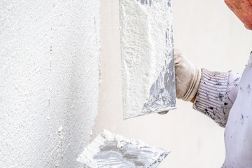 Construction worker plastering and smoothing concrete wall with cement