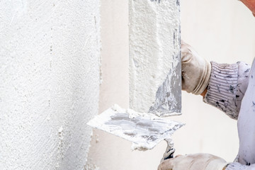 Construction worker plastering and smoothing concrete wall with cement