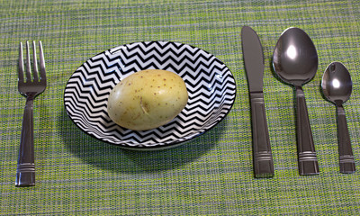 Very strict diet. Potato in a plate with black geometric pattern.