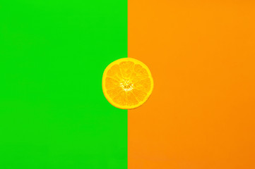 Orangenscheibe, halb aufgeschnittene Orange vor farbigem Hintergrund halb in kräftigem grün und orange