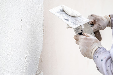 Construction worker plastering and smoothing concrete wall with cement