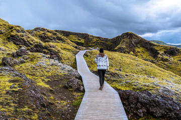 Girl teenager is following wooden foot pass to the crater Tjarnargigur in Lakagigar volcanic fissure area in Southern highlands of Iceland © sasha64f
