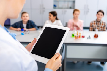 Partial view of chemistry teacher holding digital tablet with blank screen