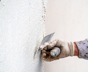 Construction worker plastering and smoothing concrete wall with cement