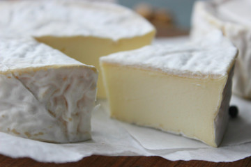 Camembert cheese. Farm products, rustic cheese. Natural cheese, round head of cheese with Camembert mold, cut on a wooden Board surrounded by fragrant spices. Cheese plate for gourmets.