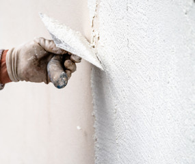 Construction worker plastering and smoothing concrete wall with cement