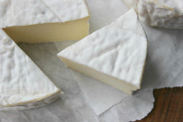 Camembert cheese. Farm products, rustic cheese. Natural cheese, round head of cheese with Camembert mold, cut on a wooden Board surrounded by fragrant spices. Cheese plate for gourmets.