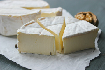 Camembert cheese. Farm products, rustic cheese. Natural cheese, round head of cheese with Camembert mold, cut on a wooden Board surrounded by fragrant spices. Cheese plate for gourmets.