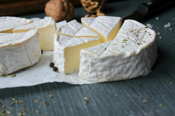 Camembert cheese. Farm products, rustic cheese. Natural cheese, round head of cheese with Camembert mold, cut on a wooden Board surrounded by fragrant spices. Cheese plate for gourmets.