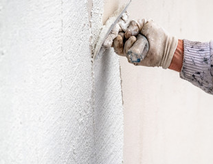 Construction worker plastering and smoothing concrete wall with cement