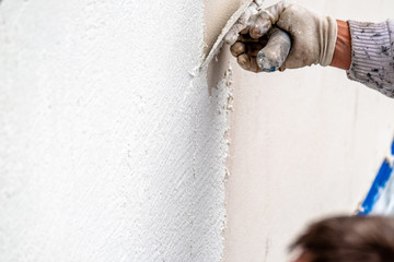 Construction worker plastering and smoothing concrete wall with cement