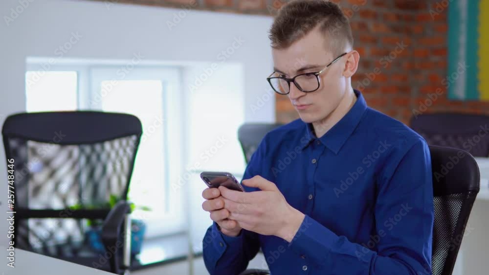 Aufkleber portrait young worker in startup company using app on smartphone or checking email sitting in loft o