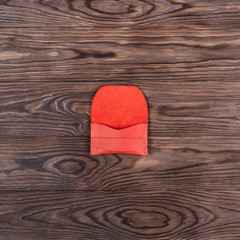 Flat lay photo of red colour handmade leather one pocket cardholder. Stock photo on wooden background.